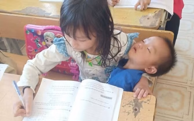 Dân mạng xót xa với hình ảnh bé gái vùng cao vừa viết bài vừa bế em ngủ say trên tay