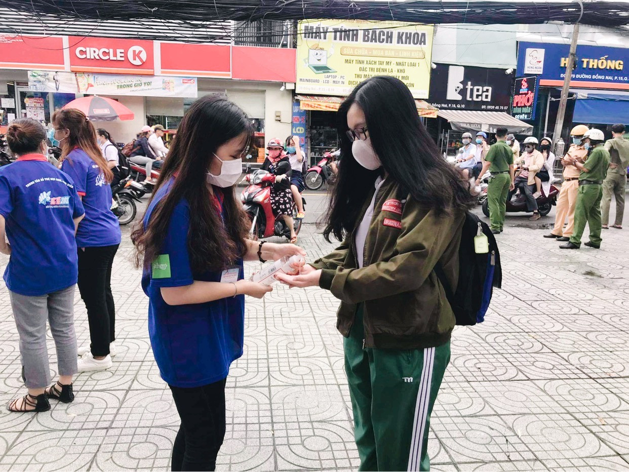 Sinh viên tiếp sức mùa thi hỗ trợ các điểm thi thực hiện biện pháp sát khuẩn cho thí sinh. Ảnh: Thục Văn. Teen “check-in” điểm thi tốt nghiệp THPT giữa sự “bảo vệ” của đội ngũ y tế, công an ảnh 2
