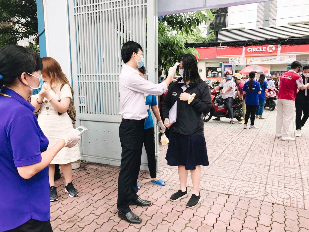 Thí sinh được đo thân nhiệt và bắt buộc đeo khẩu trang khi đến điểm thi - Ảnh: Thục Văn. Teen “check-in” điểm thi tốt nghiệp THPT giữa sự “bảo vệ” của đội ngũ y tế, công an ảnh 1