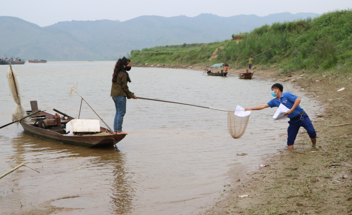 Một tình nguyện viên Đoàn xã Thanh Giang lội ra sông Lam phát bài tập cho các em làng chài. Nghỉ học vì COVID-19, các 'shipper áo xanh” mang bài đến tận nhà cho học sinh ảnh 2