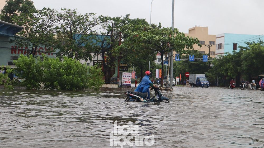 Sáng 17/10, đường số 2 Khu Công nghiệp Hòa Khánh giao Nguyễn Lương Bằng nước đã ngập hơn nửa bánh xe, người đi xe máy phải dắt bộ vì không thể khởi động được xe. (Ảnh: Ngọc Trâm) Đường phố Đà Nẵng hóa sông, người dân đổ ra chèo thuyền, bắt cá mặc thành phố can ngăn ảnh 1