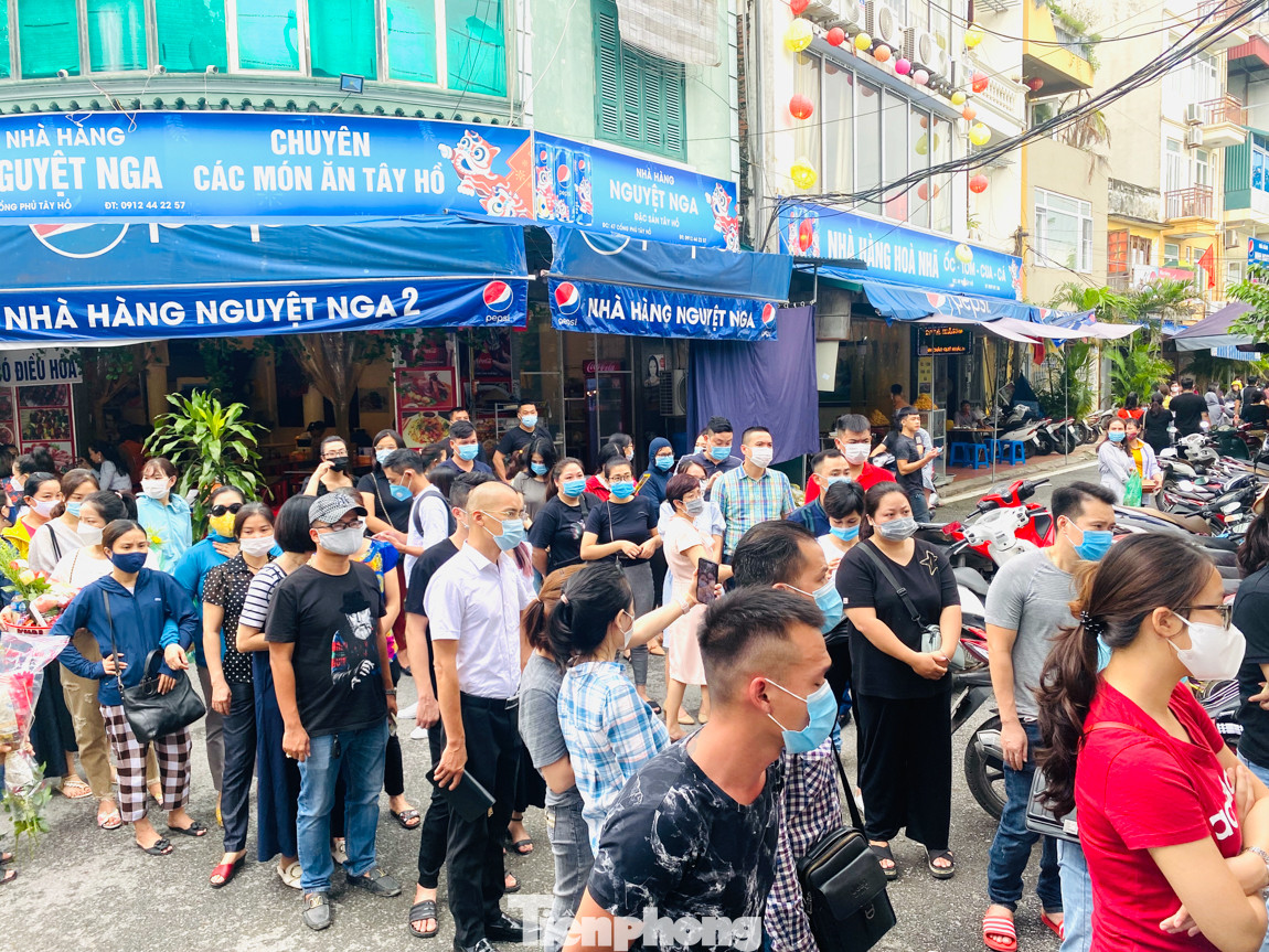 Dù phải đợi rất lâu nhưng số đông người dân đi lễ trưa nay kiên quyết bám trụ chờ đợi đến cùng chứ không chịu ra về dù lực lượng chức năng liên tục phát loa thông báo, nhắc nhở. Theo ghi nhận của phóng viên TPO, tại các cửa vào, ra đều trang bị dung dịch sát khuẩn nhưng hầu như mọi người vẫn còn thái độ chủ quan, không sử dụng. Các bàn ghi sớ bên ngoài cổng đều chật kín người. Phía bên trong Phủ, lượng người đứng lễ vái vọng từ ngoài cũng rất đông, gần như không còn một khoảng trống. Bên trong đền, phủ chật ních người. Các bàn đặt lễ đều quá tải, nhiều người phải đặt lễ chồng lên nhau. Quá giờ trưa, lượng người vẫn tiếp tục ùn ùn đổ về xếp hàng vào lễ. Bất chấp dịch COVID, 'biển người' chen nhau đi lễ Phủ Tây Hồ đầu tháng cô hồn ảnh 15