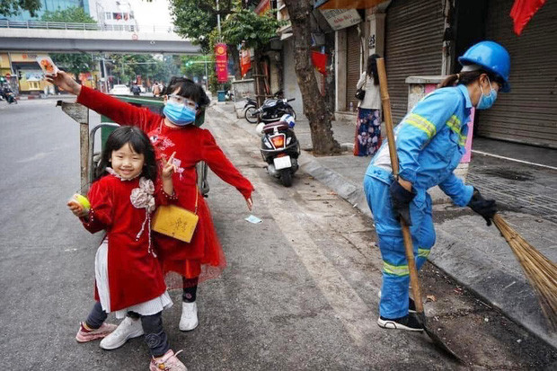 Bức ảnh 2 bé gái diện áo dài, phụ mẹ làm lao công đẩy xe rác trên phố gây xúc động ảnh 1