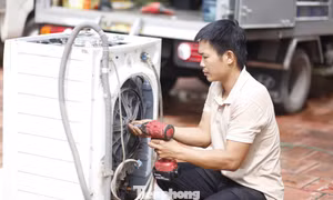 Một người thợ đang sửa máy giặt bị hỏng do nước lũ giúp người dân. Ảnh: Nguyễn Thắng