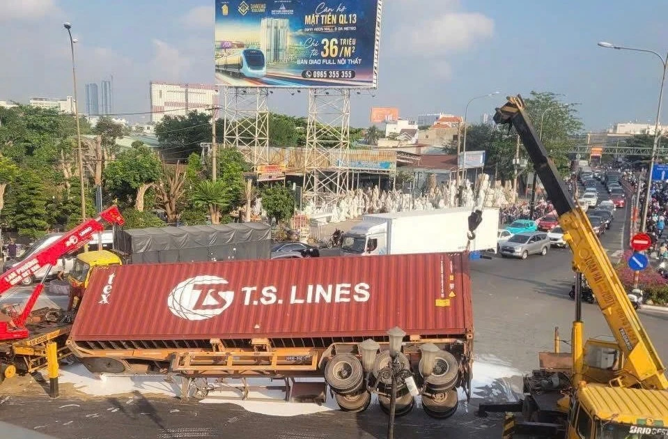 Xe container bất ngờ lật ở vòng xoay, sơn đổ trắng mặt đường lúc rạng sáng