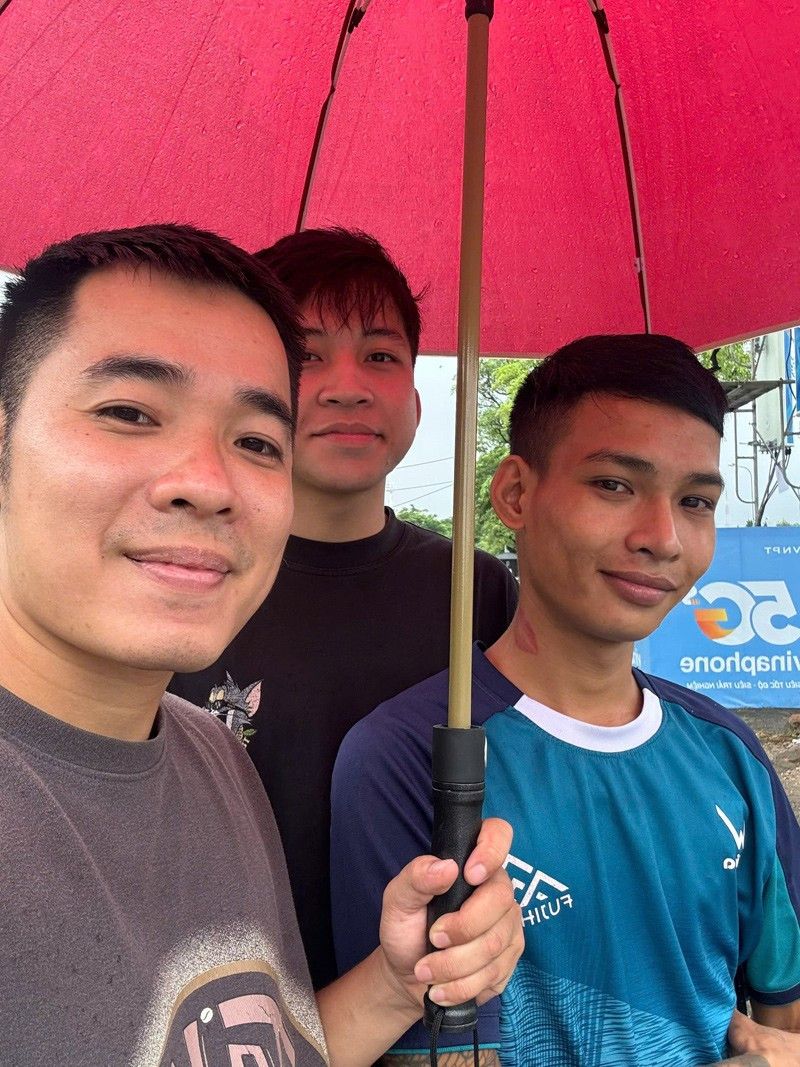 Hiếu (người cầm ô) thấy vui khi có thể lan tỏa việc tốt giữa ngày mưa ngập. viec-tot.jpg