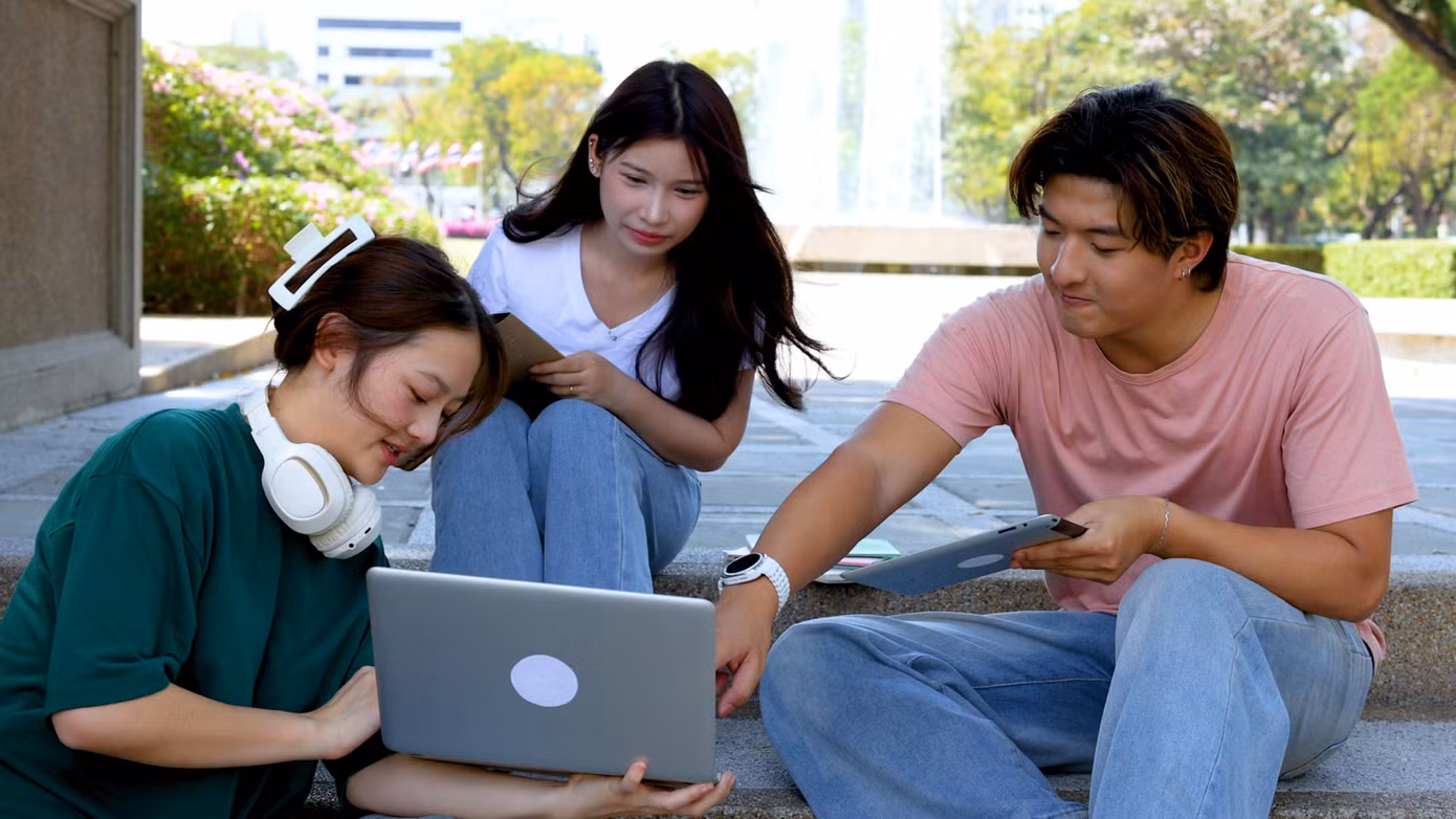 asian-university-students-collaborating-outdoors-campus-steps-with-laptop-tablet.jpg