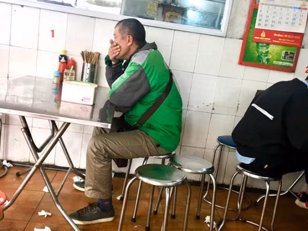 Tài xế trung niên ôm mặt kìm nén để không bật khóc sau khi nhận cuộc gọi từ quê nhà