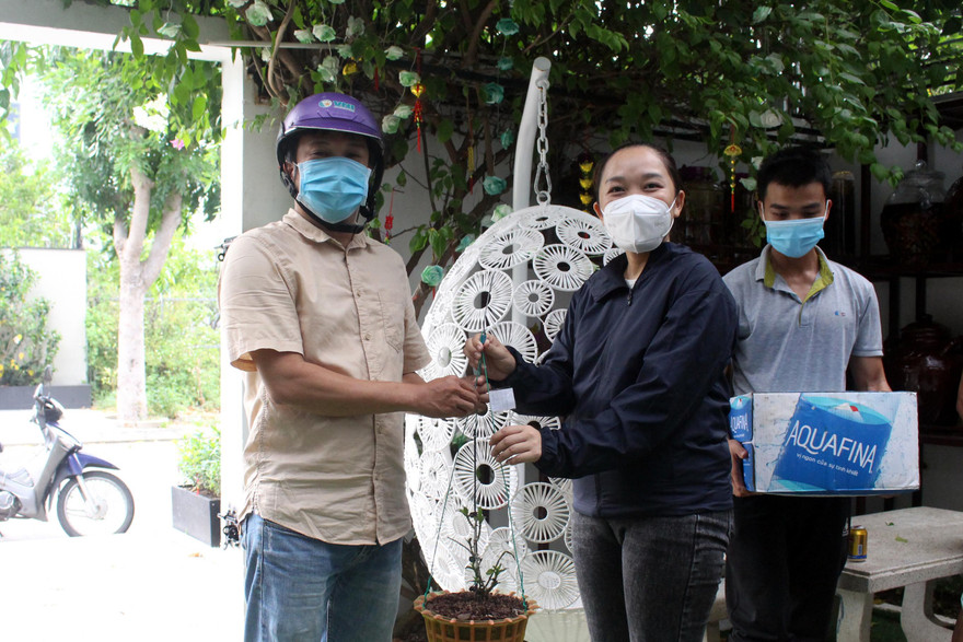 Chậu lan rừng phi điệp được Thảo (áo đen) bán cho khách hàng với giá... 2 thùng nước lọc. Toàn bộ số nhu yếu phẩm này sẽ được hỗ trợ cho các chốt kiểm dịch và khu phong tỏa. Ảnh: Giang Thanh