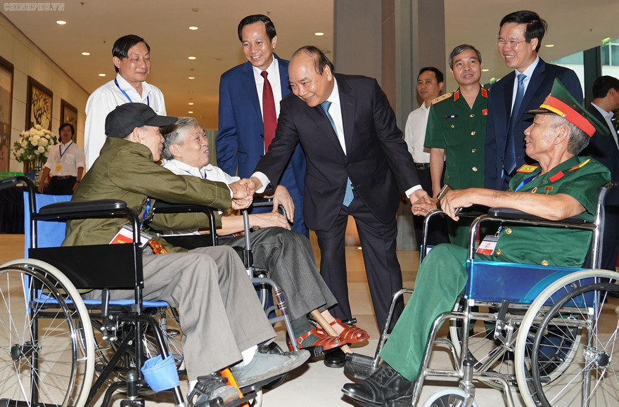 Thủ tướng thăm hỏi các đồng chí thương binh nặng tới dự buổi gặp mặt. Ảnh: VGP/Quang Hiếu