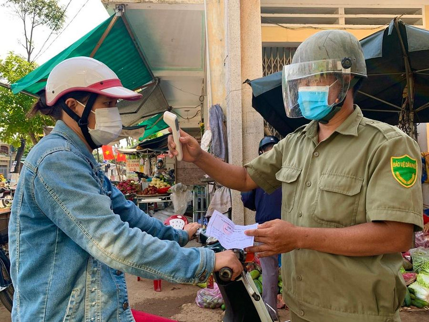 Người dân trước khi vào chợ đều phải xuất trình phiếu và được đo thân nhiệt. Ảnh: Nguyễn Ngọc