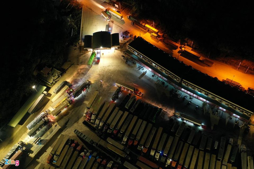 22h tối 17/12, khu vực bãi xe Tân Thanh (Lạng Sơn) vẫn sáng đèn. Hàng dài xe container nối đuôi nhau, nhích từng đoạn để được vào trong. Đây là khu vực tài xế trả hàng cho thương lái hoặc chờ thông quan để xuất khẩu nông sản sang Trung Quốc.
