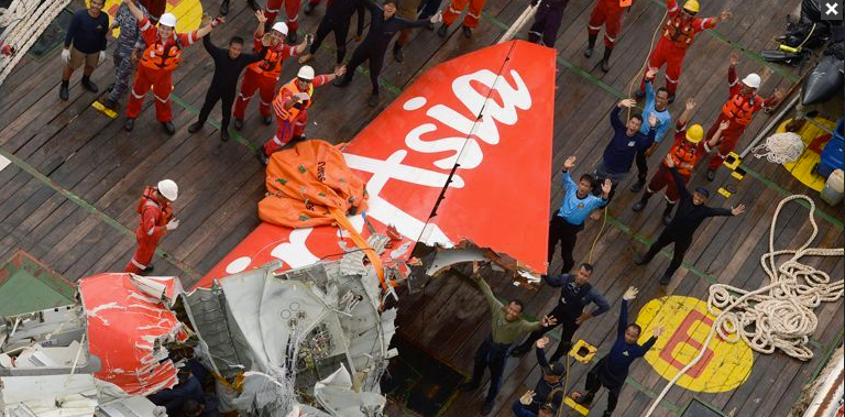 Đội trục vớt đứng cạnh phần đuôi máy bay AirAsia vừa được vớt lên, vẫy trực thăng cứu hộ