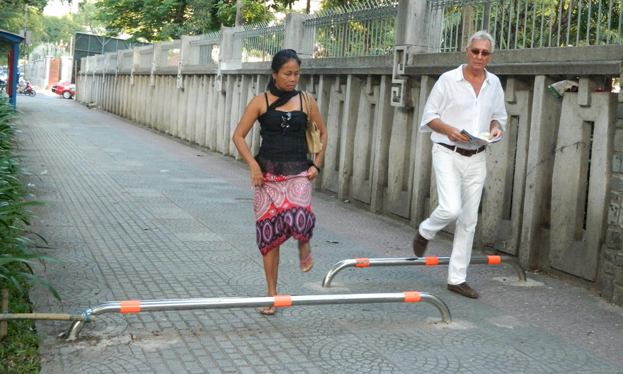 Du khách nước ngoài phải quan sát khi bước qua barie để tránh bị vấp té.