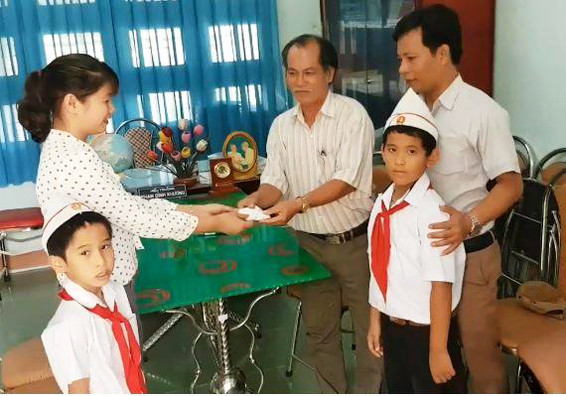 Hai em học sinh cùng lãnh đạo nhà trường bàn giao lại túi đựng vàng cho công an xã. Ảnh: X.V