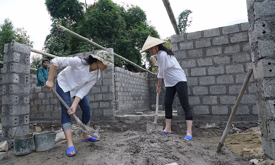 Các thí sinh trộn xi măng để xây trường học.