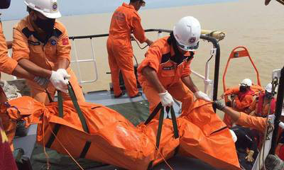 Lực lượng cứu hộ đưa thi thể một thuyền viên lên bờ.