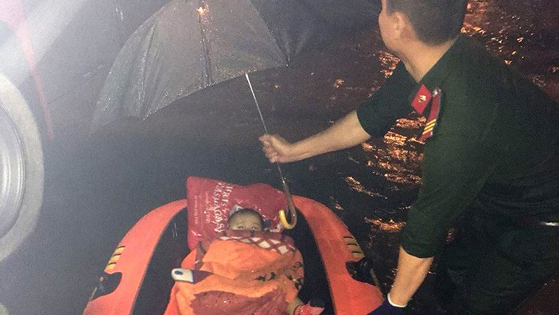 Công an quận Thanh Khê giải cứu 1 phụ nữ mang thai cùng hai con nhỏ ra khỏi khu vực ngập sâu. Ảnh: CACC
