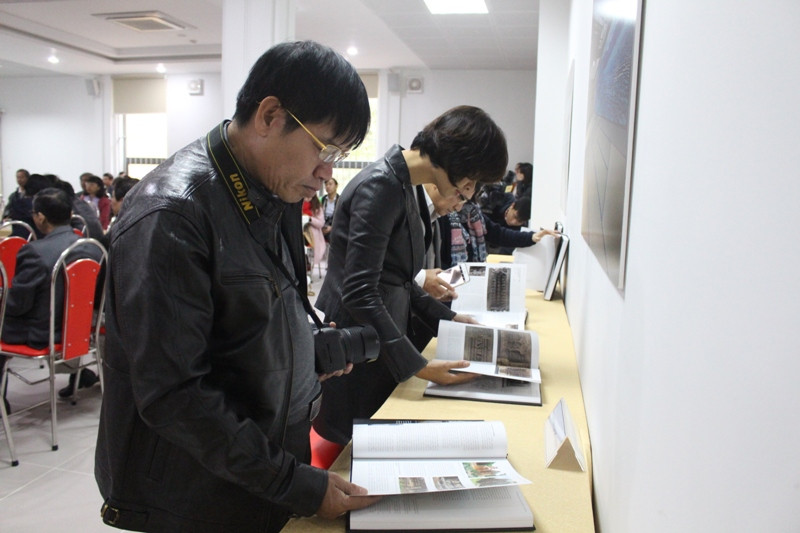 Các khách tham quan thích thú với cuốn sách ảnh mới ra mắt. Ảnh: Giang Thanh