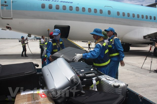 Nhân viên bốc xếp hành lý ký gửi từ hầm hàng máy bay lên xe vận chuyển. (Ảnh: Việt Hùng/Vietnam)