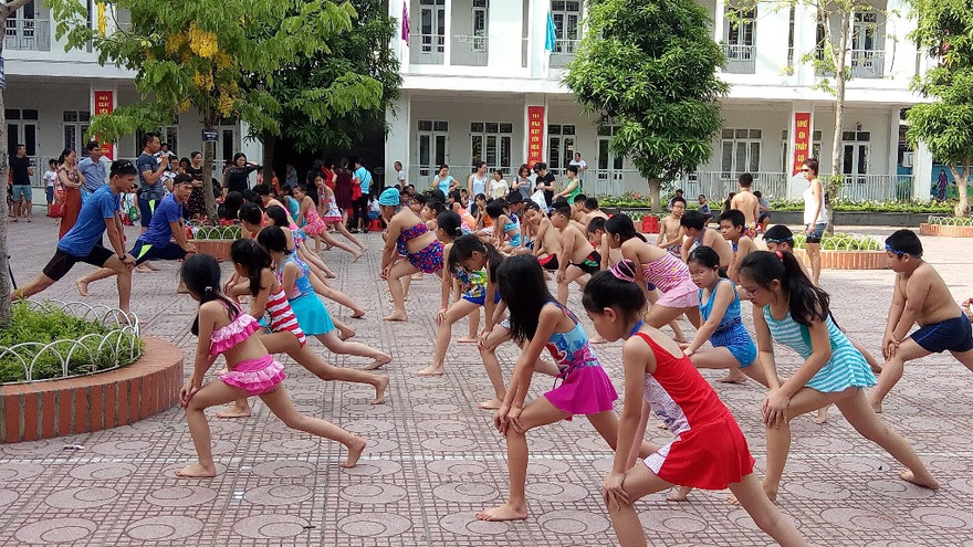 HLV hướng dẫn học sinh khởi động và thực hành tại bể bơi