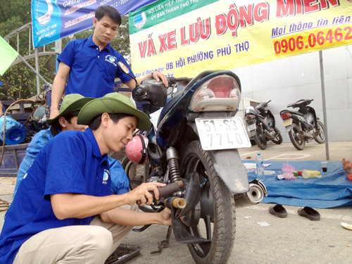  Các thanh niên tình nguyện vá xe miễn phí - Ảnh: Lê Thanh 