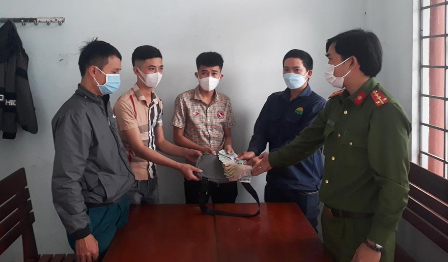 Anh Lê Văn Chung (thứ 2 từ phải sang) bàn giao số tiền nhặt được cho người mất - ảnh Huyền Oanh 