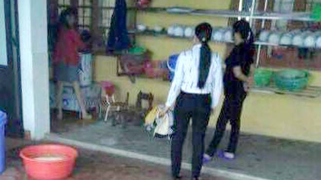 Cô hiệu trưởng Vũ Thị Hằng (áo hồng) đang ôm rồi dốc đầu cháu H vào máy vặt lông gà và hô cắm điện để “cháu không khóc nữa”. (Ảnh cắt từ clip do gia đình cung cấp cho báo chí)