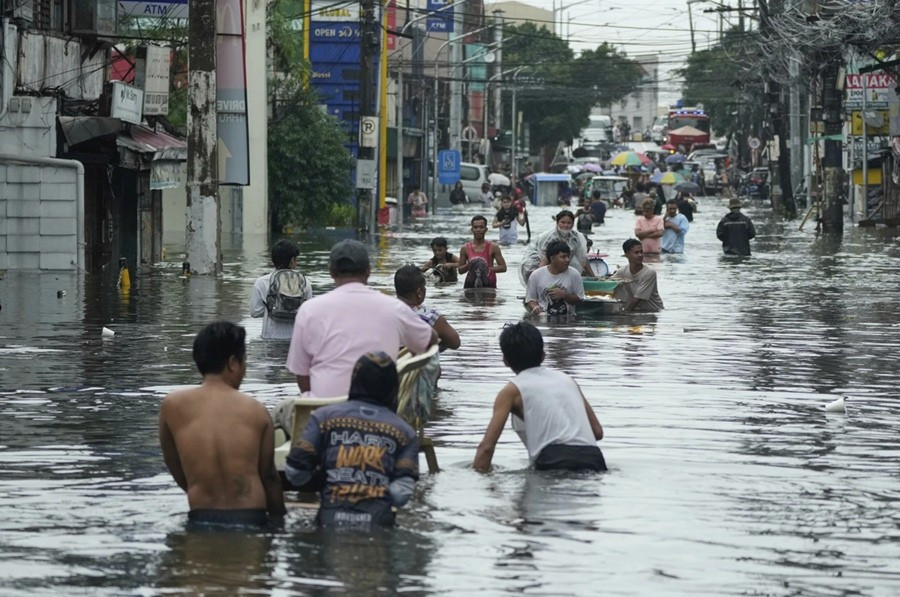 Người dân lội trên đường ngập nước do ảnh hưởng của bão Co-may ở thành phố Malabon (Philippines). Ảnh: Aaron Favila/ AP. flood.jpg