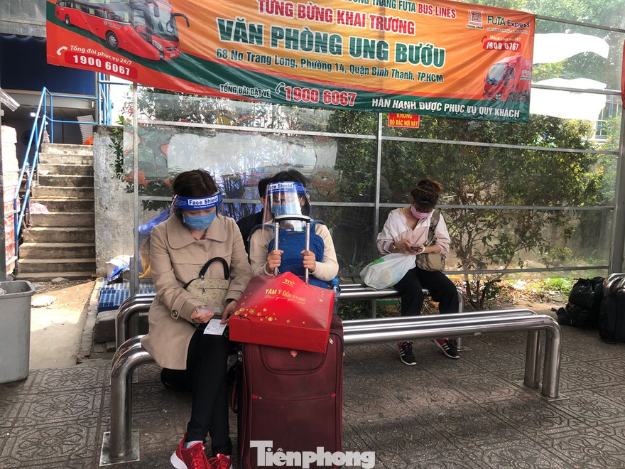 Hành khách đội mũ chống giọt bắn chờ xe khách