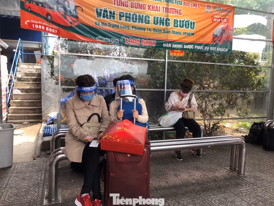 Hành khách đội mũ chống giọt bắn chờ xe khách