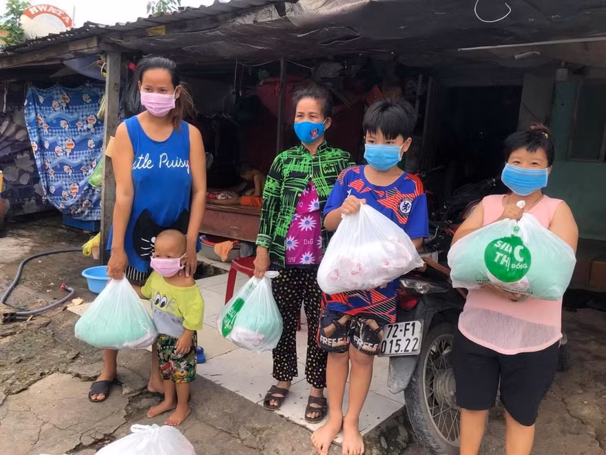 Chị Trần Thị Thu Trúc (bìa trái) vui mừng vì nhận được phần thực phẩm thiết yếu