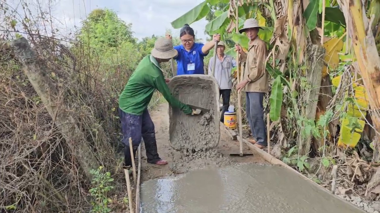 Đội trưởng nhóm tình nguyện Trần Song Hà đẩy xe chở bê tông làm đường. Ảnh: Hòa Hội tp-18.jpg