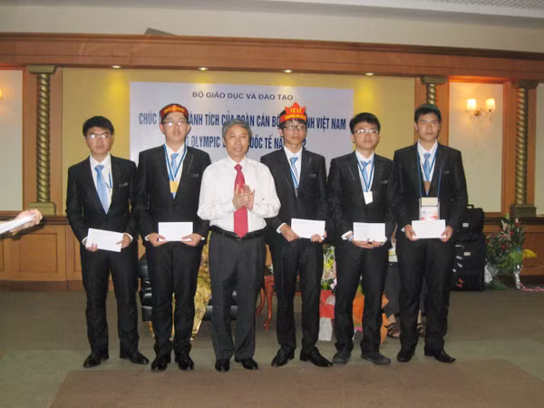 Đội tuyển học sinh Việt Nam dự IPho 2012 ở Estonia và ông Ngô Kim Khôi, Cục trưởng Cục Khảo thí & Kiểm định Chất lượng Giáo dục, Bộ GD&ĐT tại sân bay Nội Bài. Long đứng bên phải ông Khôi, Hải đứng bên trái Ảnh: Quý Hiên