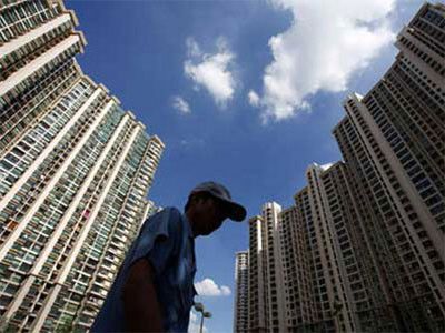 Một người lao động nghèo đi ngang qua khu nhà cao tầng ở Thượng Hải. Ảnh: China Daily