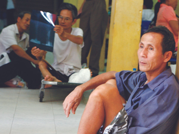 Bệnh nhân ngồi ngoài hành lang Bệnh viện Việt Đức (Hà Nội) chờ khám bệnh sáng 1-8 Ảnh: Hồng Vĩnh