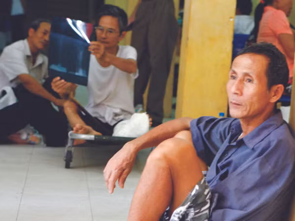 Bệnh nhân ngồi ngoài hành lang Bệnh viện Việt Đức (Hà Nội) chờ khám bệnh sáng 1-8 Ảnh: Hồng Vĩnh