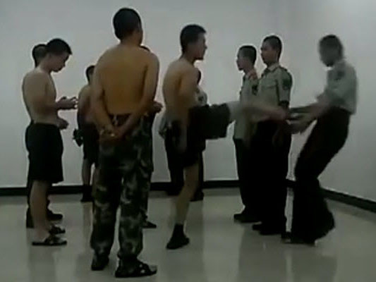 Trong một ảnh cắt từ clip, tay lính cũ đạp chân thẳng vào bụng anh lính mới