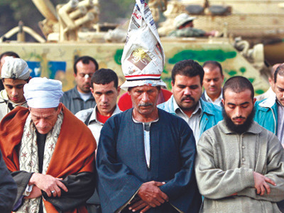 Những người biểu tình chống Tổng thống Mubarak cầu nguyện bên cạnh xe tăng của quân đội Ai Cập
