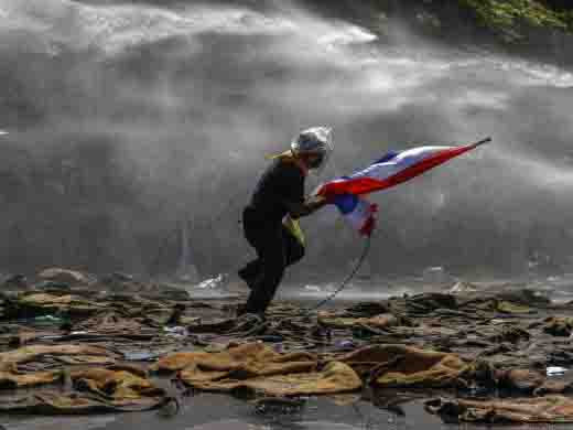 Một người bỏ chạy khi cảnh sát dùng vòi rồng trấn áp biểu tình