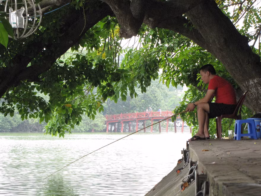 Ngồi ghế nhựa, uống trà đá thản nhiên câu cá ở Hồ Gươm. Ảnh: Trường Phong