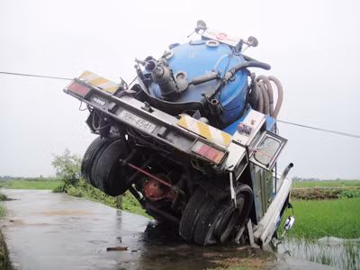 Con trâu sắt sáu bánh đâm đầu xuống ruộng, đuôi vắt ngang đường bê tông. Lốp xịt. Bình ắc quy không còn