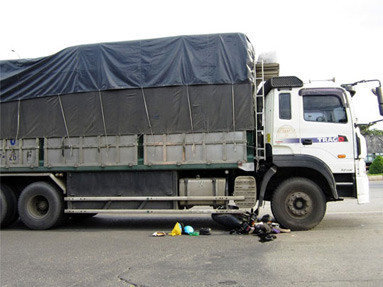 Cha con thoát chết khi xe máy cuốn vào gầm xe tải