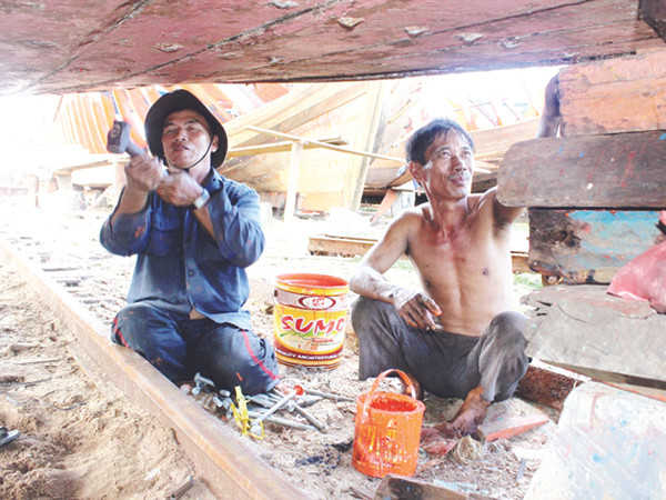 Ông Bùi Lành (phải) sửa tàu sau chuyến câu mực Trường Sa. Tàu ông chưa thể nhận hỗ trợ vì không có dấu xác nhận. Ảnh: Nguyễn Huy