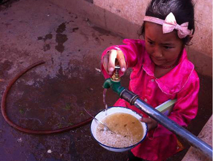 Em bé vặn vòi nước dẫn từ sông trộn cùng cơm để ăn