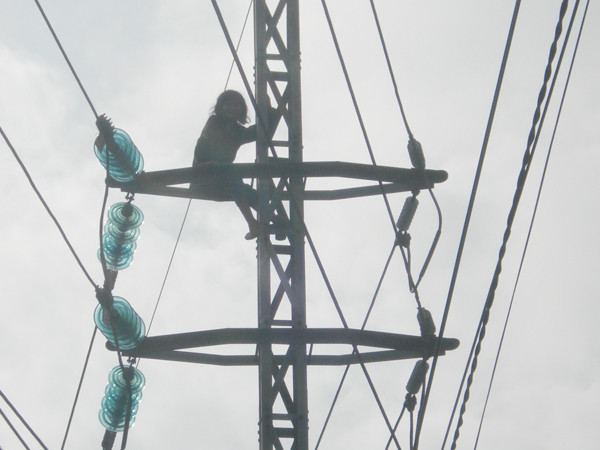 Một phụ nữ ngồi trên trụ điện cao thế