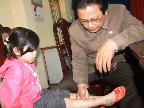 Ông Hoàng Cầm kiểm tra vết bầm tím trên chân cháu Vy