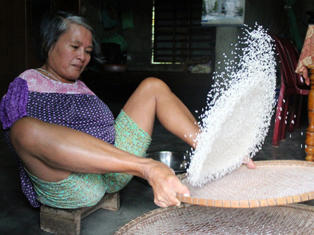 Người phụ nữ sàng gạo bằng chân để kiếm sống