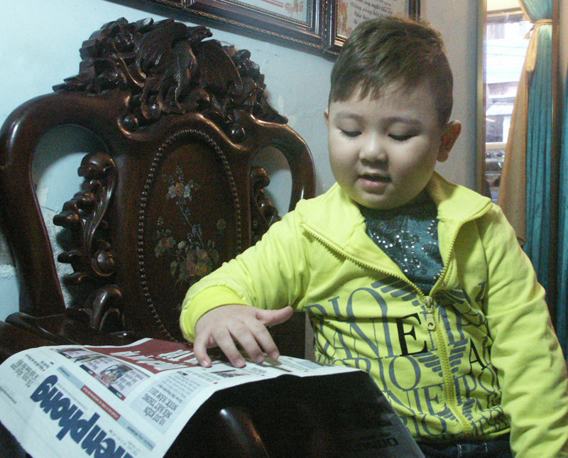 Bé Khang đọc báo Tiền Phong cho cả nhà nghe. Ảnh: Phạm Duẩn