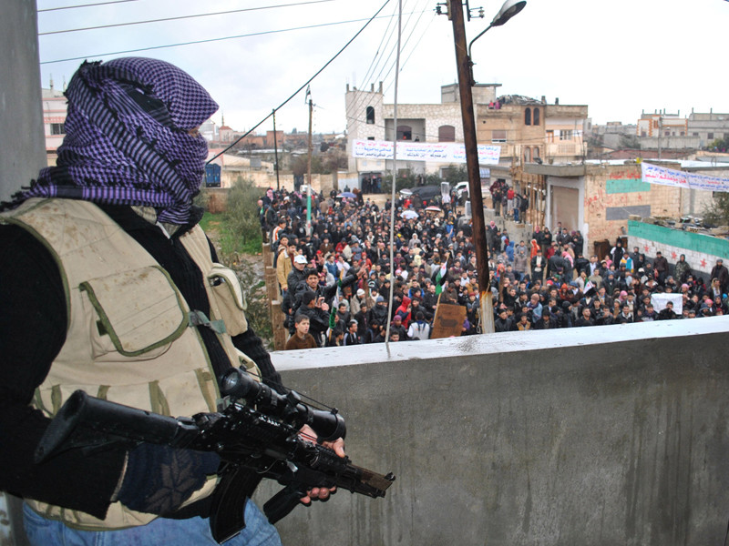 Biểu tình chống chế độ Assad ở thành phố Homs (hai người cầm súng là lính chính phủ đào ngũ) Ảnh: Mint Press